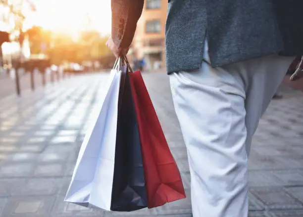 Photo of Concept of man shopping and holding bags, closeup images. Close up of paper shopping bags in male hand.