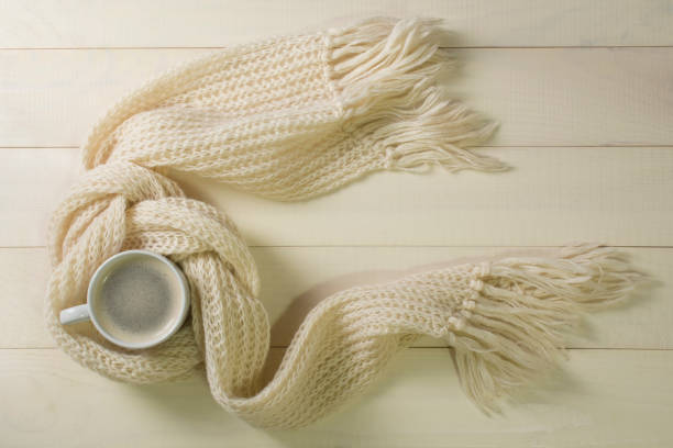 istock Winter concept. Hot coffee and white woolen scarf on white table background 1061827628