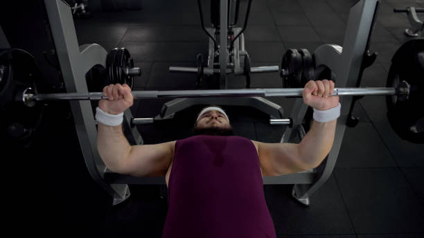 istock Motivated fat man hardly lifting barbell, exhausting workouts, healthy lifestyle 1061832852