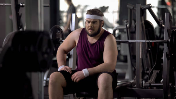 istock Upset fat man thinking over weight problems, desire to lose weight, gym workout 1061833076