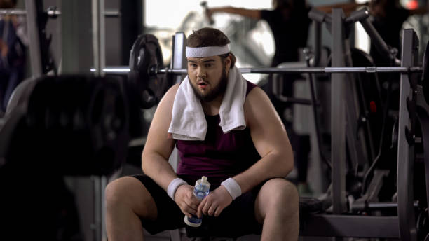 istock Obese male drinking water after barbell exercise, restoring aqua balance, diet 1061833078