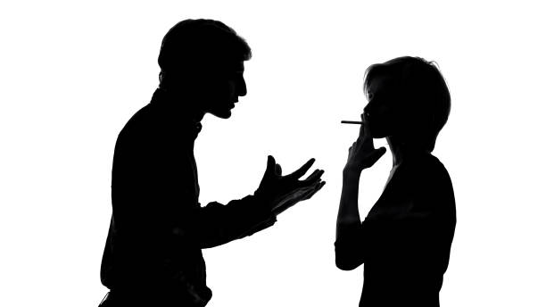 istock Angry man shouting at his girlfriend smoking cigarette in front of him, quarrel 1061833162