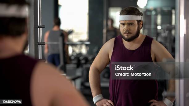 Unhappy Overweight Man Looking At His Mirror Reflection In Gym Diet And Sport Stock Photo - Download Image Now