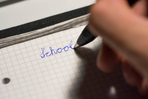 child writing school word with ball pen on paper