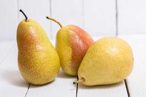 Close view of a tasty portuguese pears on a white wooden background.