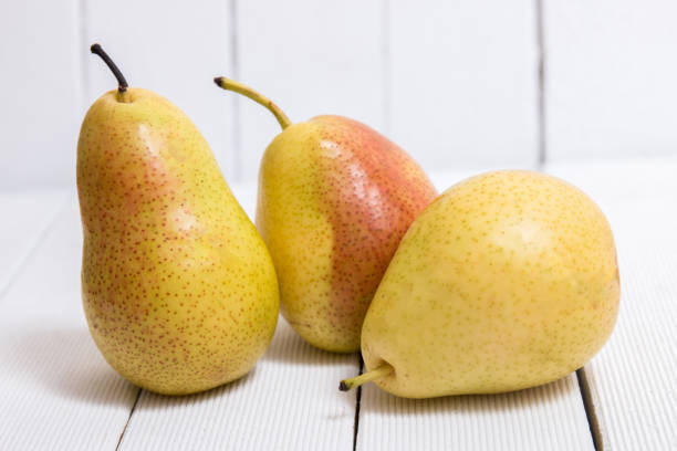 Tasty portuguese pears Close view of a tasty portuguese pears on a white wooden background. perfect pear stock pictures, royalty-free photos & images