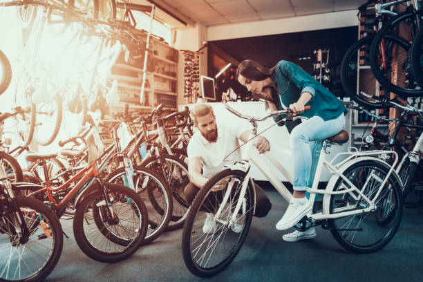 女の子がスポーツ店で売り手と都市の自転車を選択します。 - bicycle shop ストックフォトと画像