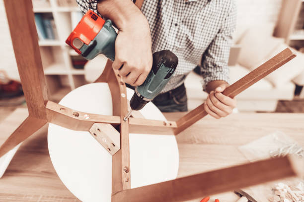 Furniture Assembler with Drill in Hands Repairs Chair. stock photo
