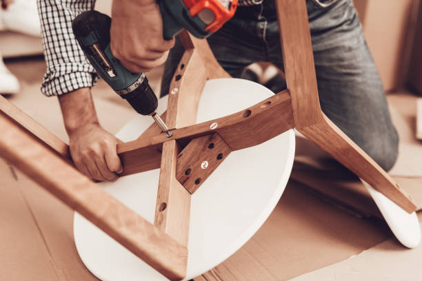 istock Furniture Assembler with Drill in Hands Repairs Chair. 1061844898