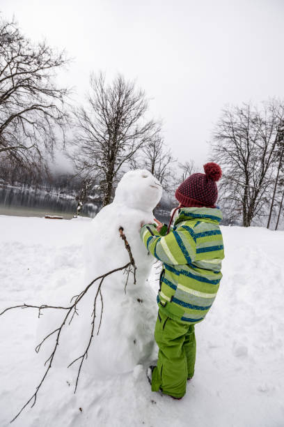 istock Boy wearing knitted cap making a winter snowman 1061845758