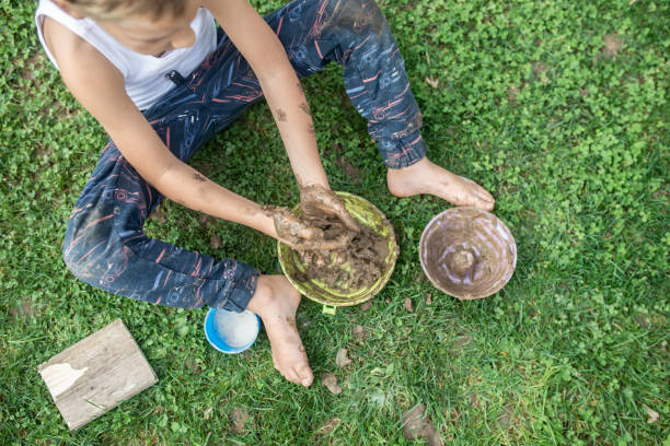 istock Top view of boy sitting in grass playing with mud 1061845896