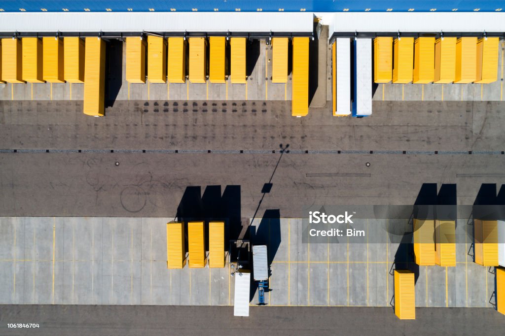 Aerial View of Cargo Containers and Distribution Warehouse Aerial view of cargo containers, semi trailers, industrial warehouse, storage building and loading docks, Bavaria, GermanyAerial view of cargo containers, semi trailers, industrial warehouse, storage building and loading docks, Bavaria, Germany Aerial View Stock Photo
