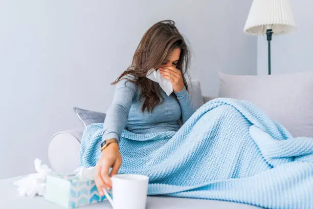 Photo of Young woman with cold blowing her runny nose