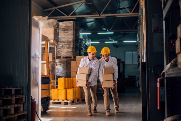 istock Coworkers carrying boxes with helmets on heads. Storage interior. 1061867430