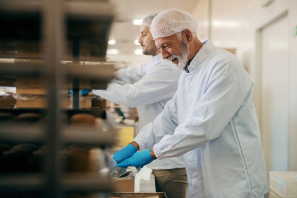 istock Workers packing cookies in boxes while standing in food factory. 1061868614
