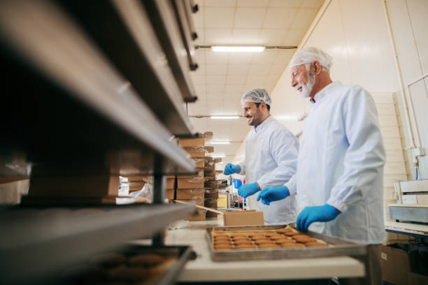 istock Workers packing cookies in boxes while standing in food factory. 1061868684