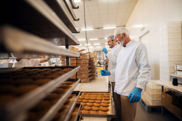 istock Workers packing cookies in boxes while standing in food factory. 1061868960
