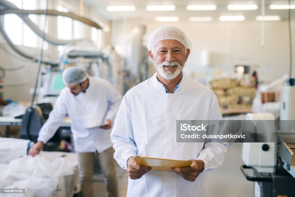 Man holding documents. Senior holding documents and standing in food factory. Food Stock Photo