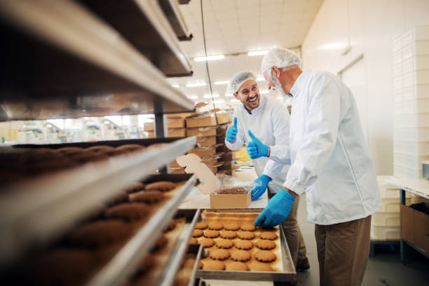 istock Workers packing cookies in boxes while standing in food factory. 1061871106