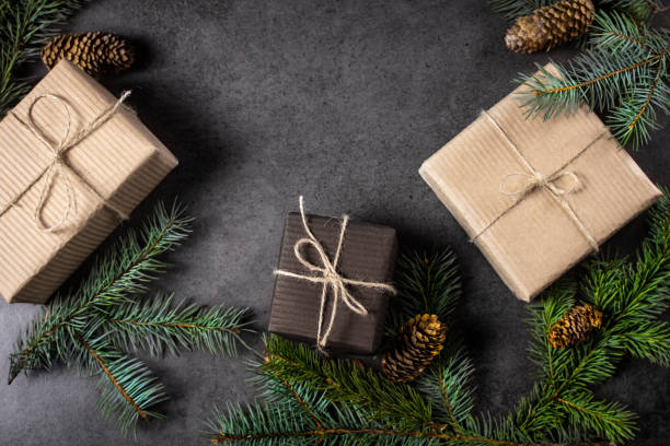 istock Black and brown paper christmas gift box with pine branches on dark texture surface. 1061871124
