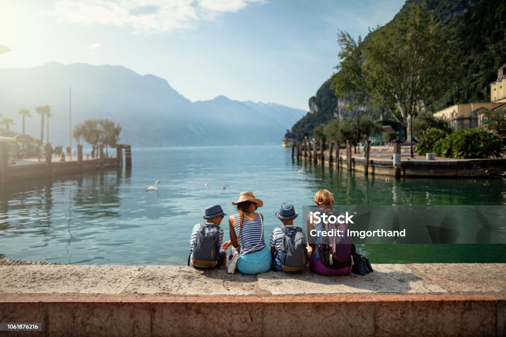 家庭坐在加爾達湖濱的海港, 享受加爾達湖的景色 - 免版稅家庭圖庫照片