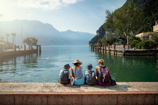 家庭坐在加爾達湖濱的海港, 享受加爾達湖的景色 - 義大利文化 圖片 個照片及圖片檔