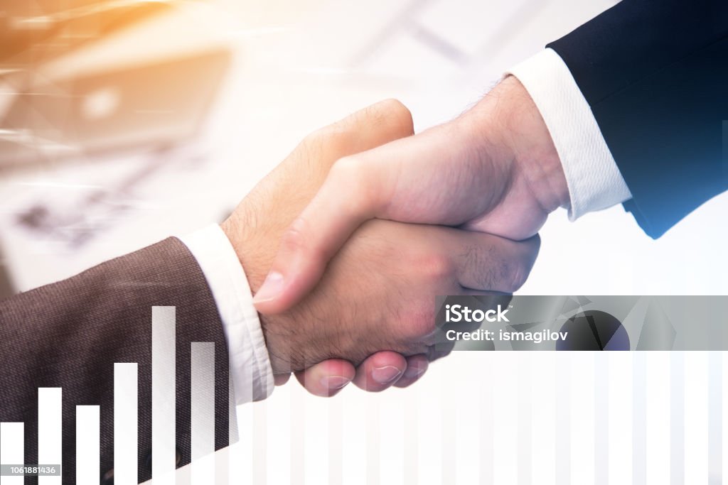 Handshake in office, graphs and diagrams Close up of two businessmen shaking hands over a blurred office background. Graphs and diagrams in the foreground. Sealing a deal concept. Toned image double exposure Adult Stock Photo Handshake in office, graphs and diagrams Close up of two businessmen shaking hands over a blurred office background. Graphs and diagrams in the foreground. Sealing a deal concept. Toned image double exposure Adult Stock Photo