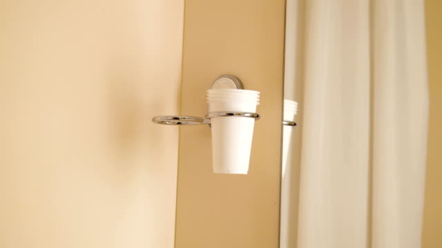 A metal cup holder mounted on the wall of the room