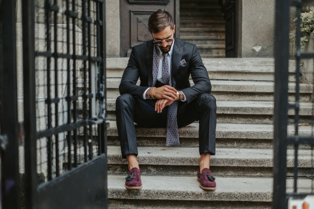 Businessman waiting on the stairs and looking at the time stock photo