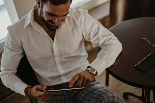 istock Elegant smiling man looking at the tablet in a cafe 1061889048