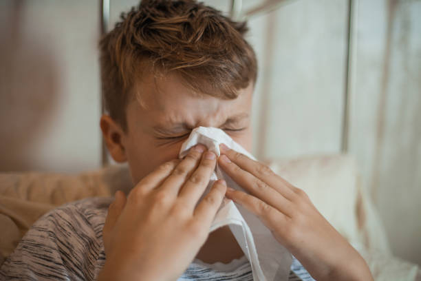 istock Boy Wiping Runny Nose With a Tissue 1061889844