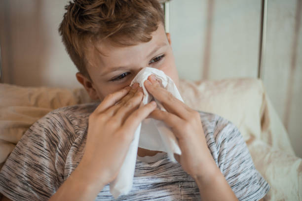 istock Boy Wiping Runny Nose With a Tissue 1061889856
