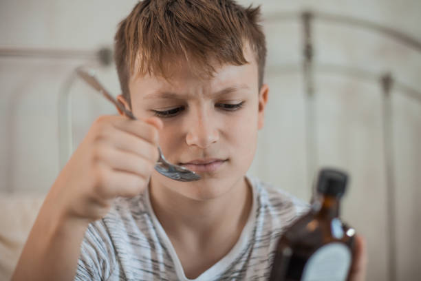 istock Young Boy Taking a Cough Syrup Medicine 1061889888