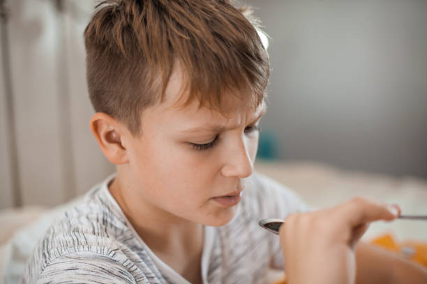 istock Young Boy Taking a Cough Syrup Medicine 1061889908
