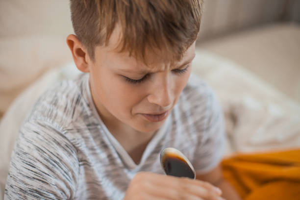 istock Young Boy Taking a Cough Syrup Medicine 1061889934
