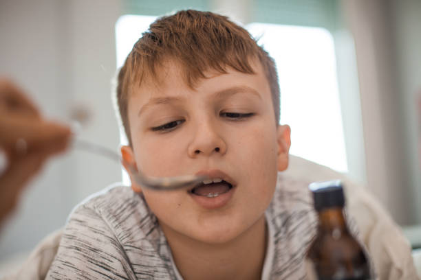 istock Young Boy Taking a Cough Syrup Medicine 1061889982