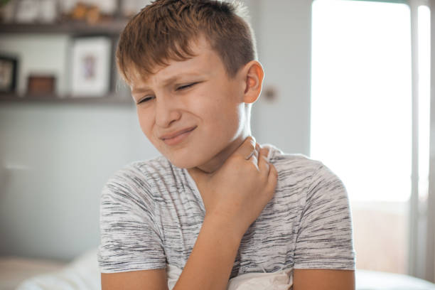 Sore Throat - Boy holding his neck in pain stock photo