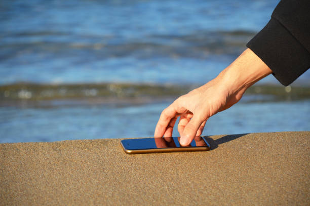 istock Human hand taking smart phone on the sand 1061890108