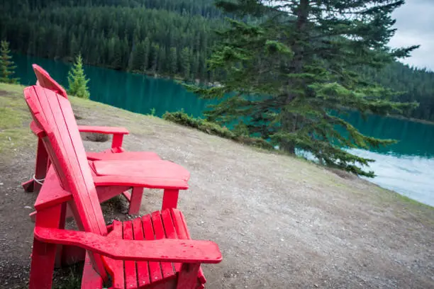 Adirondack chairs sit beside Two Jack Lake in Banff National Park in the Canadian Rockies