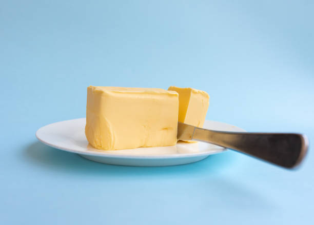 istock Organic butter on white plate with knife against blue background 1061899964