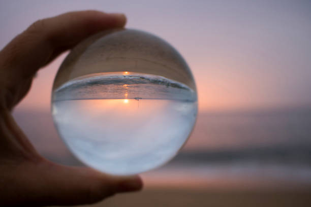 istock Pink Sunset with Boat on Horizon Captured in Glass Ball Reflection 1061902220