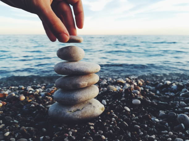 Hand putting pebbles on stones balanced zen style stock photo