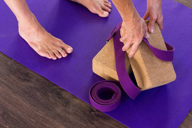 piedi di donna su tappetino viola e mani che prendono mattoni di sughero e cinghia - purple belt foto e immagini stock