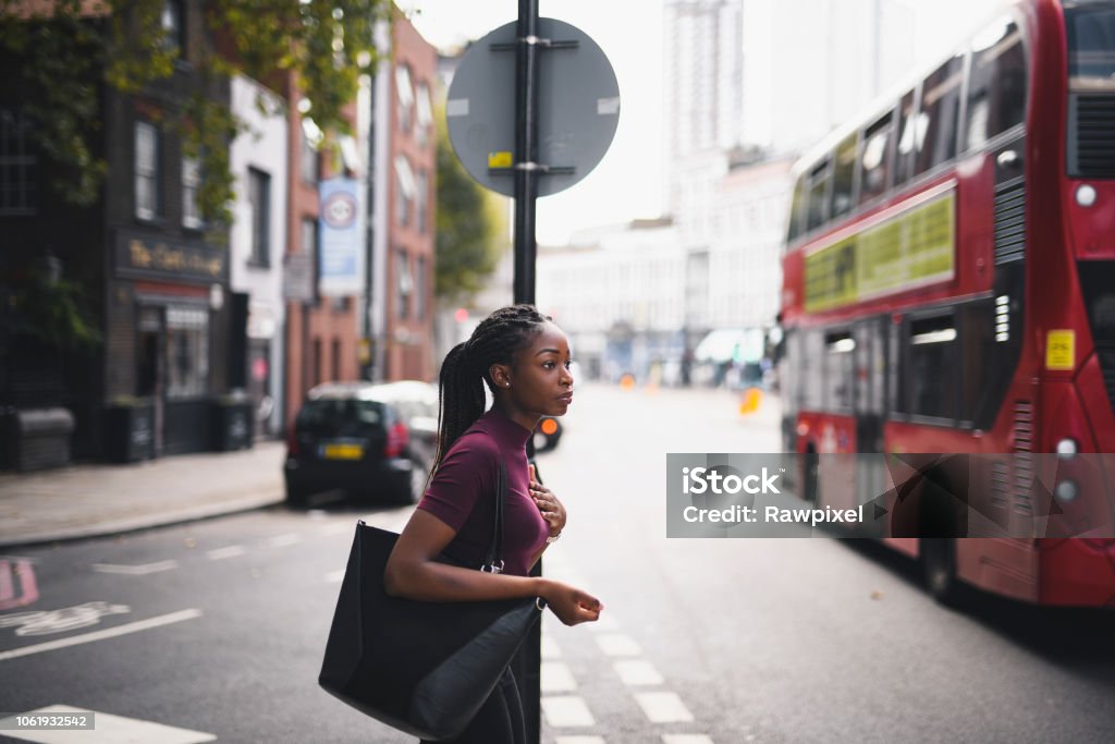 Woman with braids crossing a street in downtown London Women Stock Photo