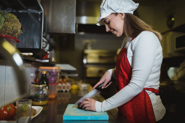 istock Woman working in the restaurant kitchen and cutting ingredients 1061955128