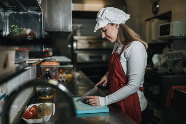 istock Woman working in the restaurant kitchen and cutting ingredients 1061955170