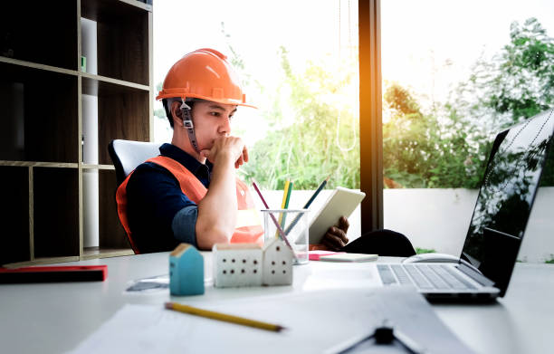 istock architect man working hand holding  tablet with laptop computer and  blueprints, inspection architectural in builder for architectural plan, sketching a construction at work site, engineer concept. 1061961822