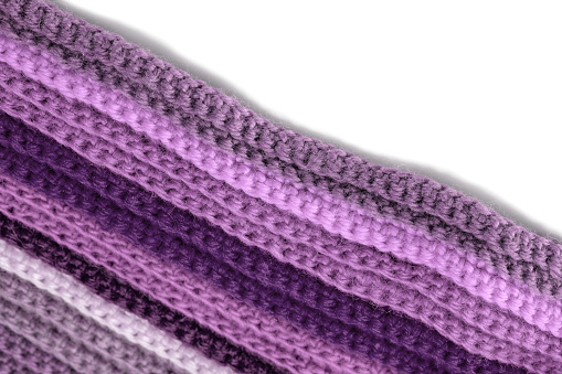 Close-up of a woolen knitted texture (in purple tones) on a white background. Space for copy.