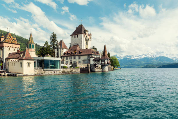 берн, швейцария - 10 мая 2016 г.: замок оберхофен в озере тун с горами на фоне швейцарии, недалеко от берна - berne switzerland thun jungfrau стоковые фото и изображения