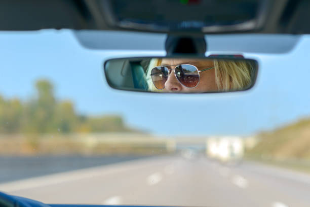 mujer conduciendo un coche en una autopista - rear view mirror car mirror sun fotografías e imágenes de stock